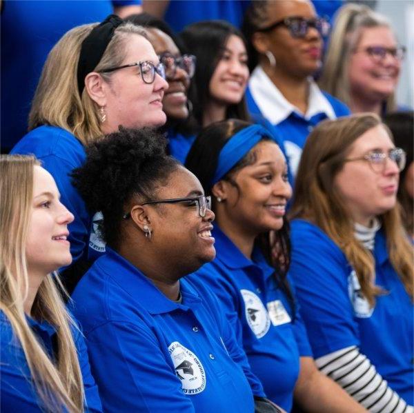 group photo of two rows of people in blue shirts